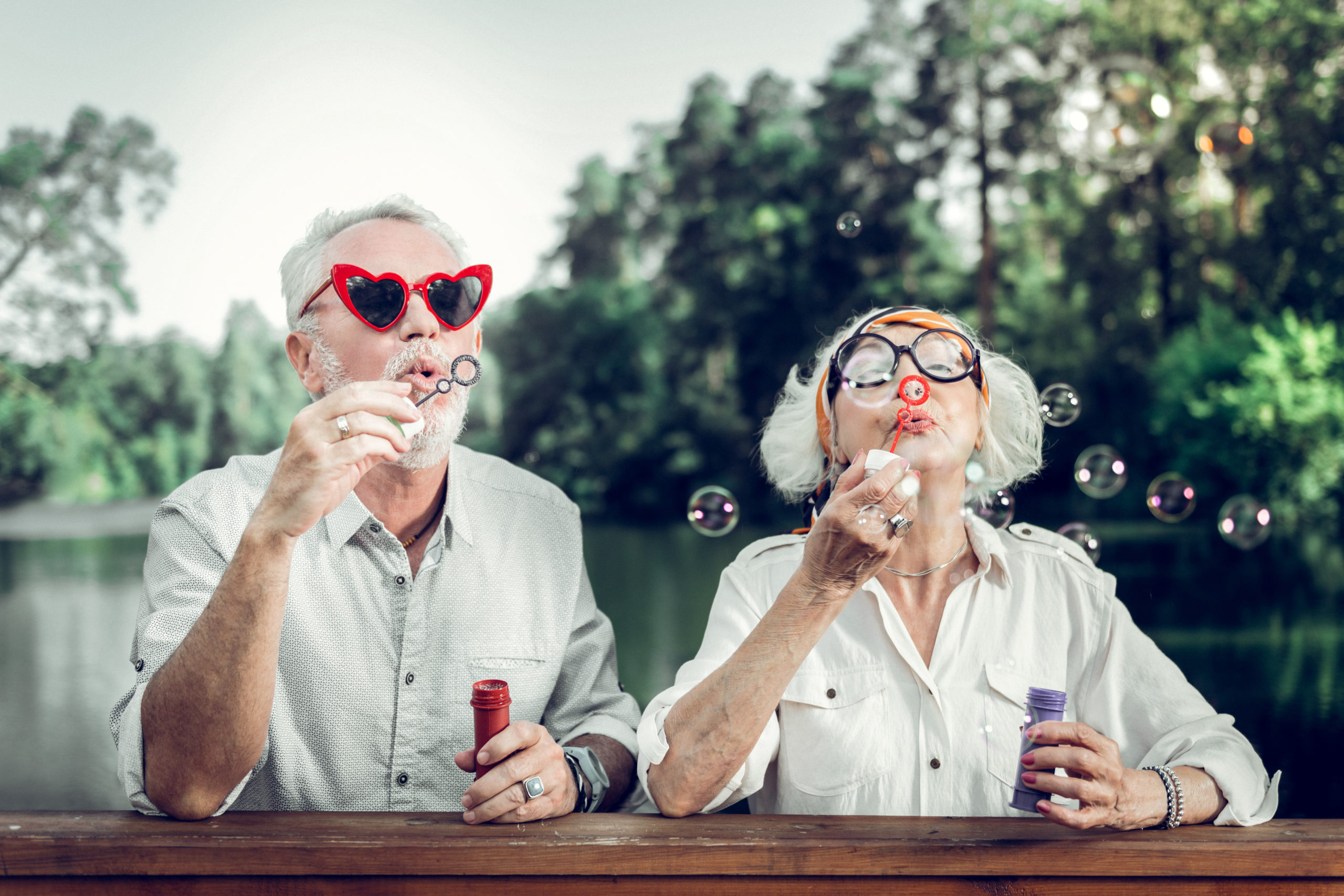 Couple âgé soufflant des bulles de savon en forme de cœur.