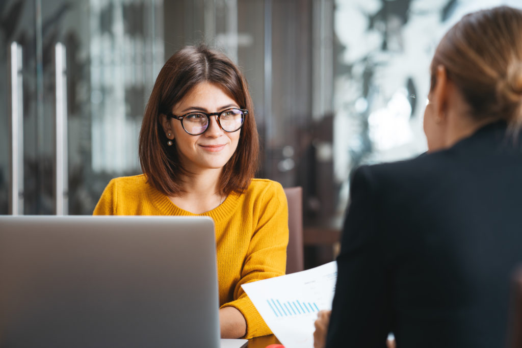 Femme en jaune souriante lors d'une réunion professionnelle.