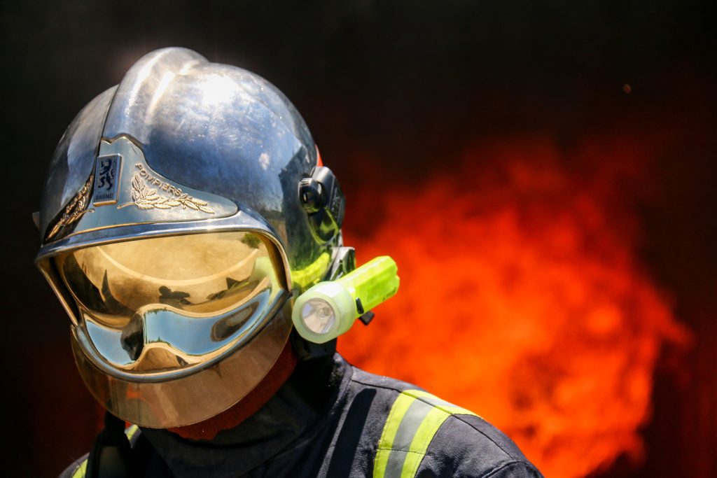Pompier avec masque devant un feu ardent.
