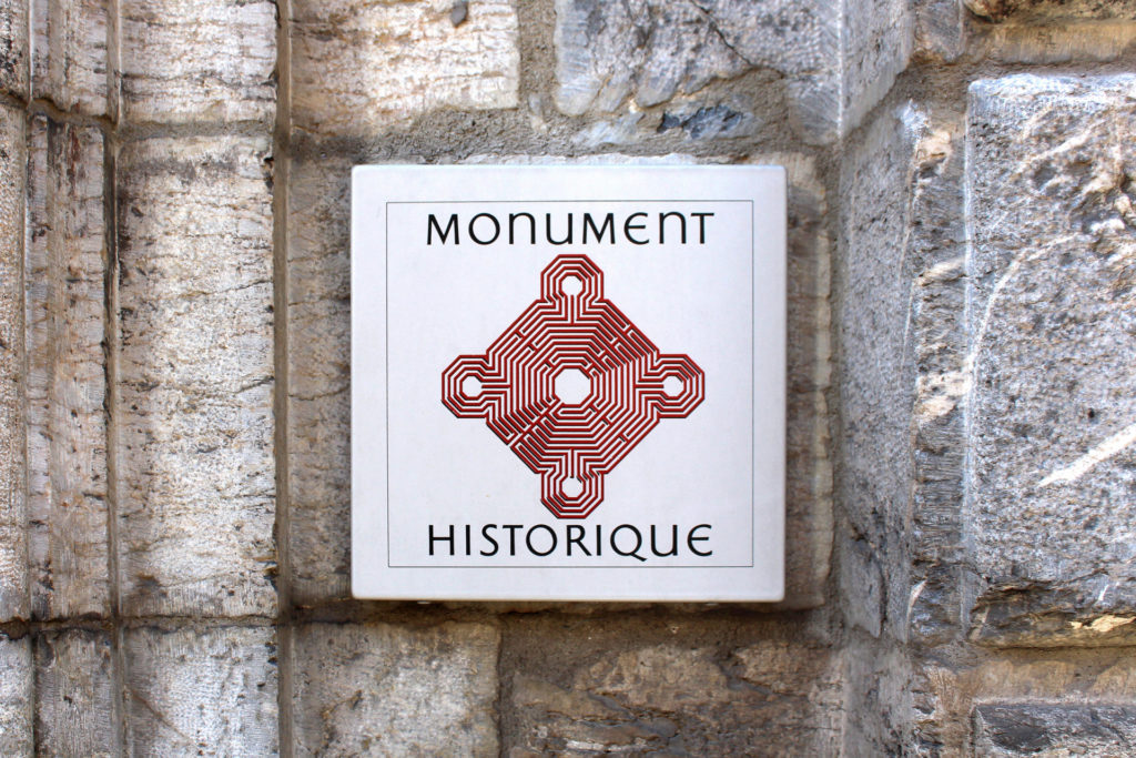 Panneau "Monument Historique" sur un mur en pierre.